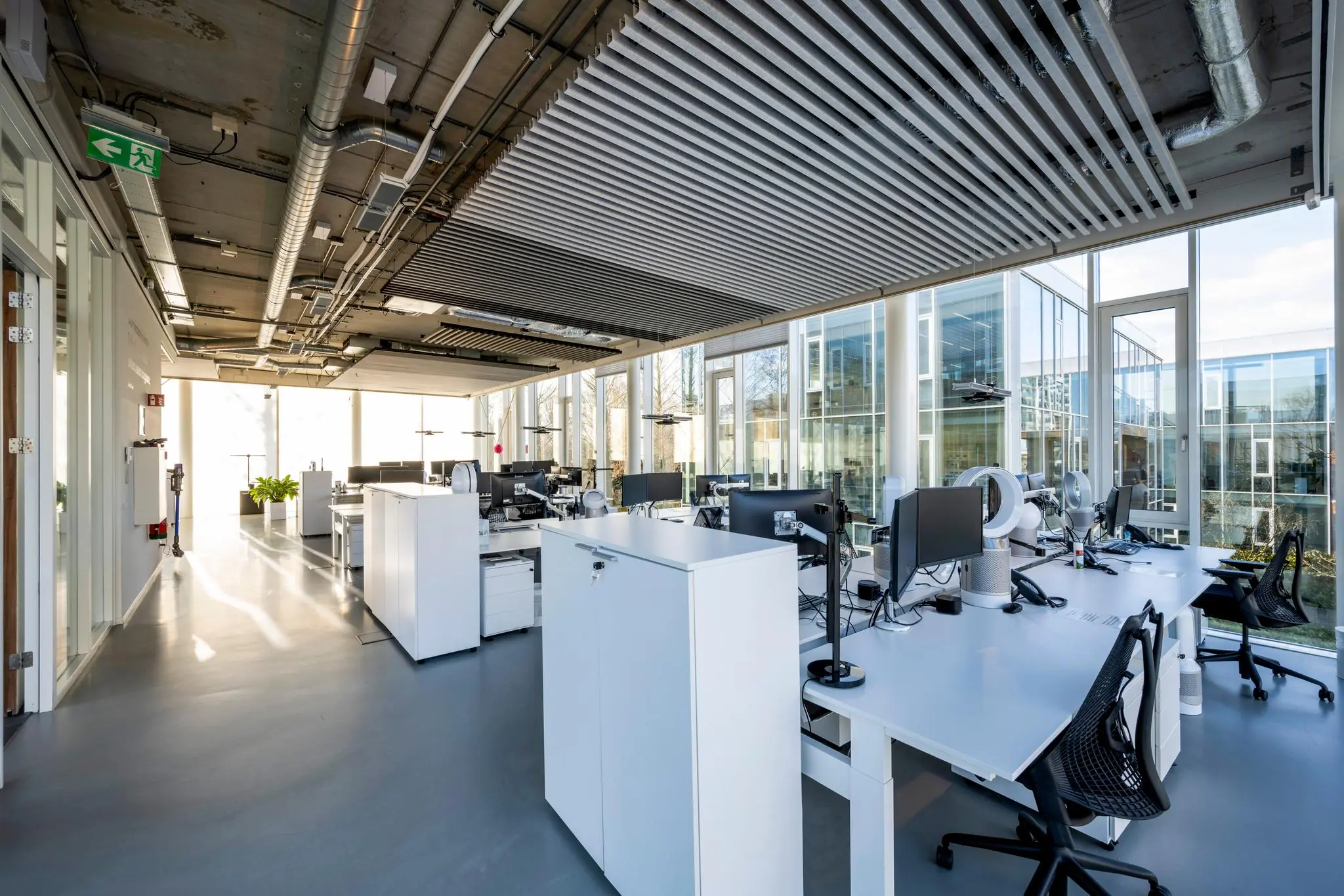 Moderne, open kantoorruimte aan de Fred. Roeskestraat met werkplekken, grote ramen en industrieel plafond.